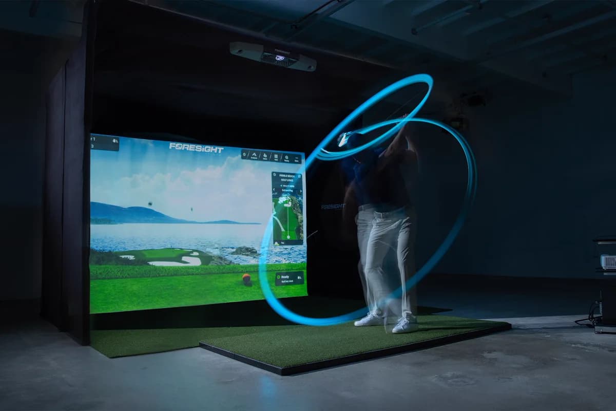 A player mid-swing in a darkened Foresight bay, the swing traced as a light trail